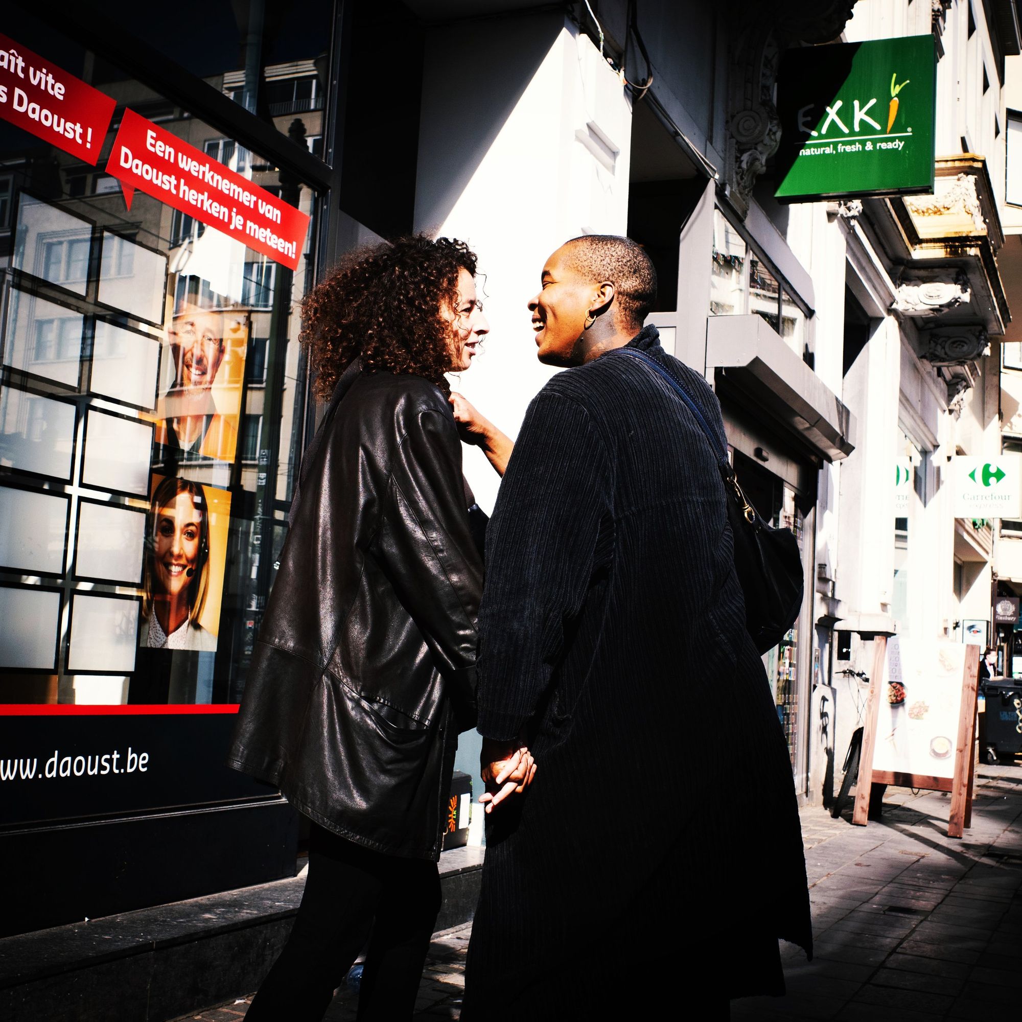 Two women laughing together outside a shop window